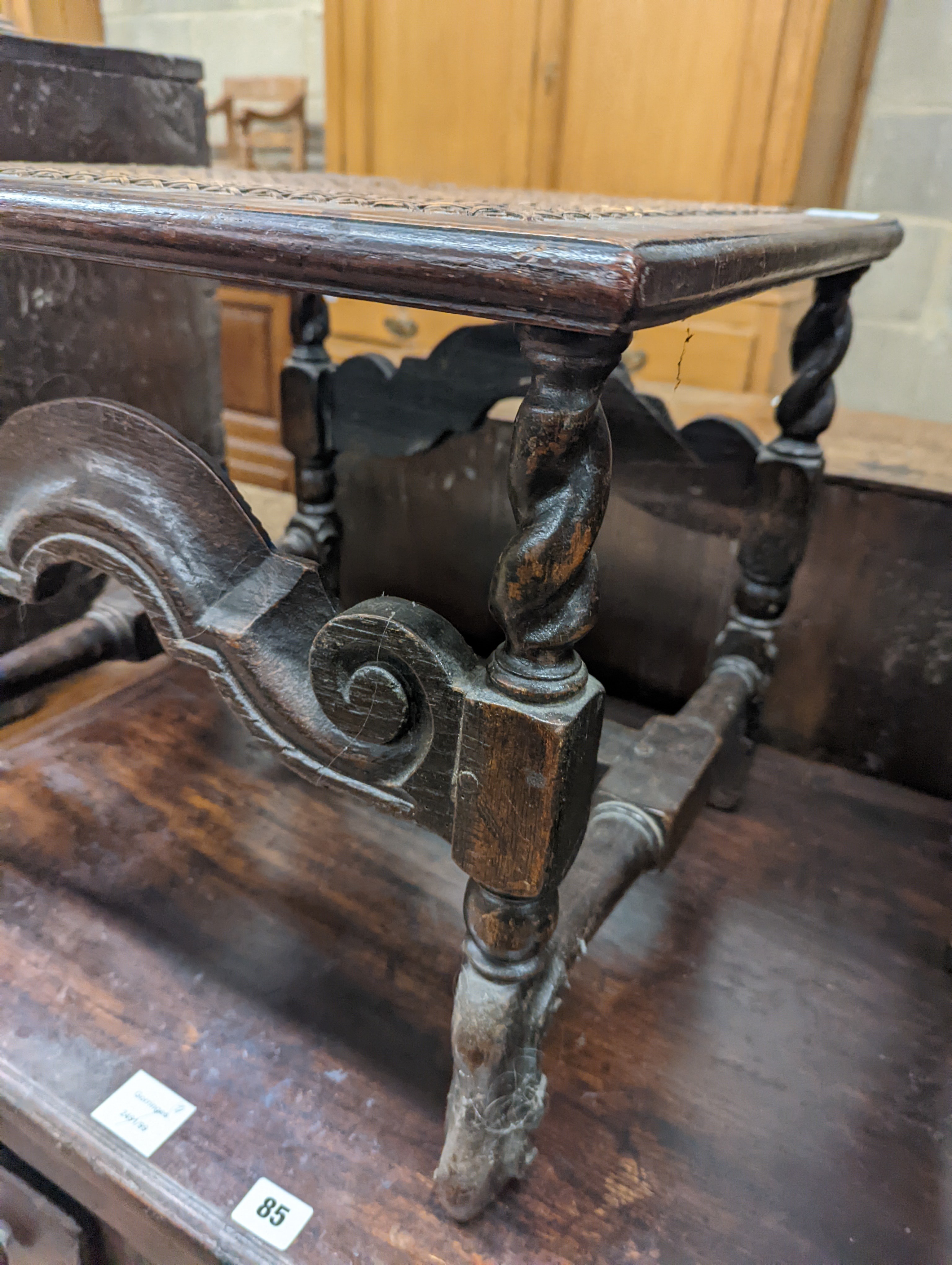 A 17th century style carved oak stool, with caned seat and H stretcher, width 47cm, depth 46cm, height 42cm